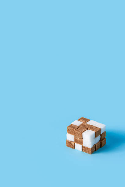 cube made of white and brown sugar cubes isolated on blue background stock photo