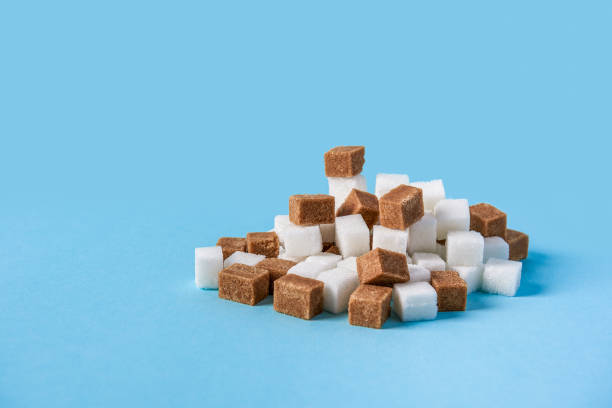 hill made of white and brown sugar cubes isolated on blue background stock photo