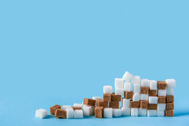 ruined wall made of white and brown sugar cubes isolated on blue background stock photo