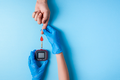 Enfermera haciendo un examen de sangre. Mano del hombre con una gota de sangre roja con tira de prueba de glucosa de sangre y medidor de glucosa photo