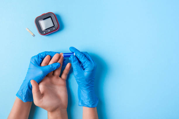 Nurse making a blood test with lancet. Man's hand with red blood drop with Blood glucose test strip and Glucose meter stock photo
