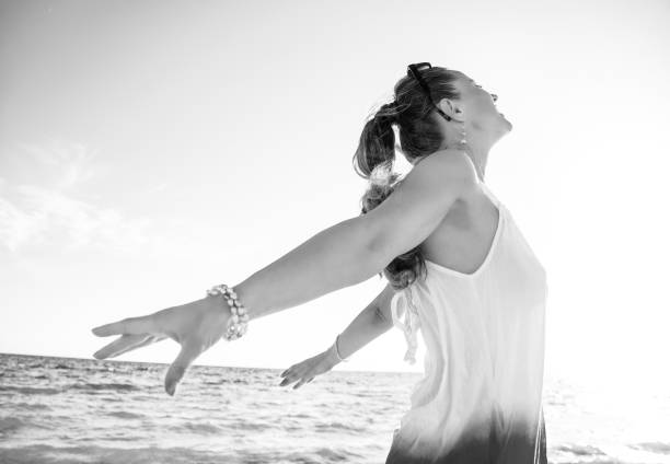 istock smiling young woman on seacoast in evening rejoicing 1032680206