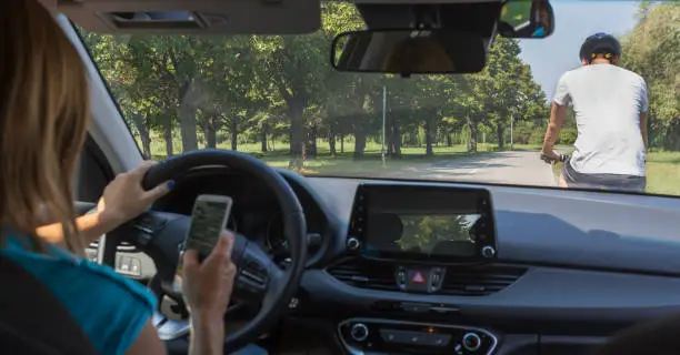 Woman driving and texting on cell phone and not paying attention to the road. Hit a man on a bicycle. Dangerous situation.