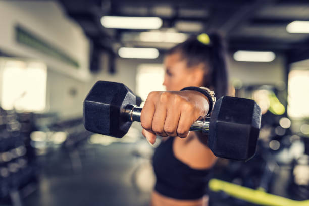 Young woman workout in gym healthy lifestyle Young woman doing shoulder exercise using dumbbells. images of female bodybuilders stock pictures, royalty-free photos & images