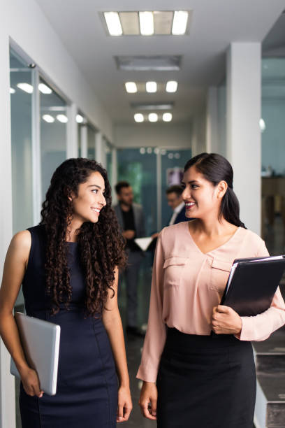 istock Two beautiful female executives looking at each other and smiling 1032703448