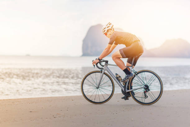 istock Young asian cyclist man ride  bicycle  the beach at the sunset 1032704004