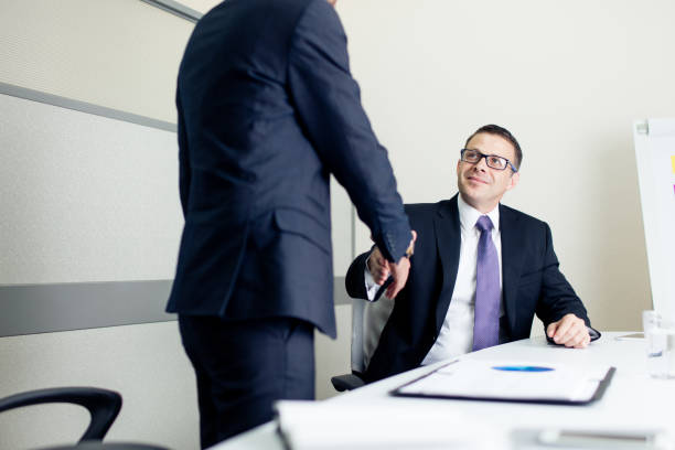 istock Two male executives shaking hands in office at work 1032704010