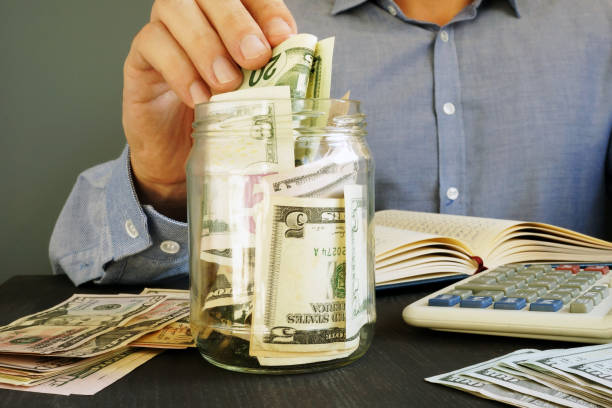 istock Man is putting dollar banknotes into the jar. Savings. 1032710932