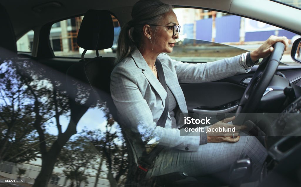 Empresaria Senior conduce a la oficina en un coche - Foto de stock de Conducir libre de derechos