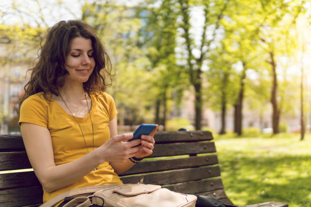 istock Beautiful young caucasian girl using phone on a bench 1032715800