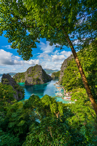 Palawan, Philippines, Asia - November 23, 2017: Palawan  view showing island of Coron, trees, rock mountains boats, long wooden bridge and nipa hut in the sea can be seen on the background