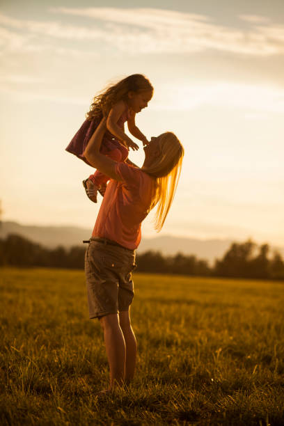 istock Mother lifting her girl on a summer evening 1032717370