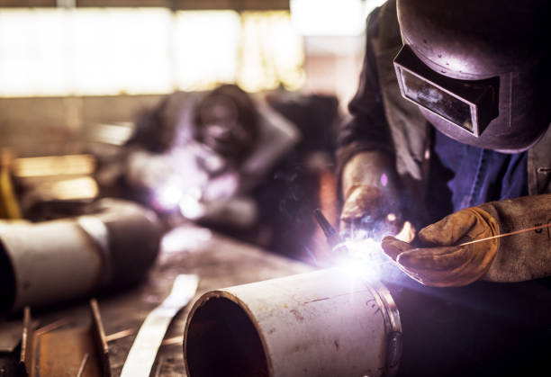 cerca de un tubo metálico tela hombre trabajador corte con una amoladora eléctrica en taller. - construction built structure building activity shipyard fotografías e imágenes de stock