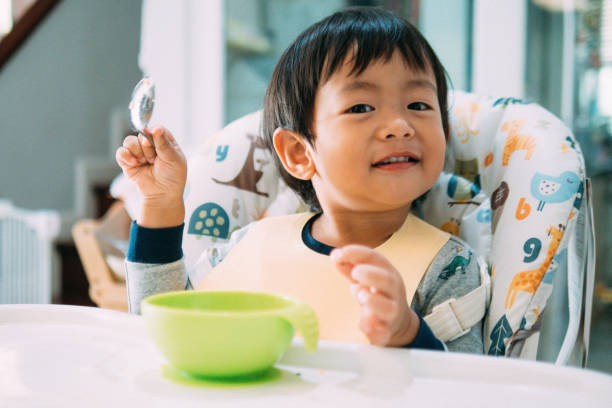 istock Asian baby boy feeding himself on high chair. 1032721224