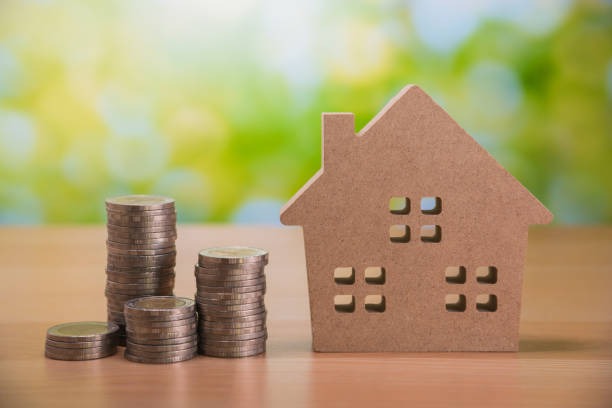 istock Cardboard Model House And Stacked Coins Over Table 1032721628