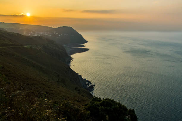 a view over exmoor national park cliffs  above the sea during sunset, a dark and dramatic view of the south west coast of great britain, uk - somerset west imagens e fotografias de stock
