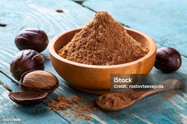 Whole Inshell Nut Cracked And Nutmeg Powder In A Wooden Bowl And Spoon On Old Blue Rustic Background Stock Photo - Download Image Now
