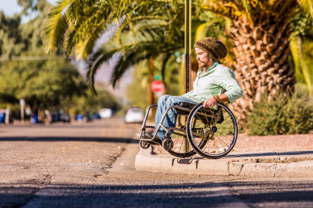 Man in Wheelchair Approaching High City Curb Young man in wheelchair approaches high city curb curb photos stock pictures, royalty-free photos & images