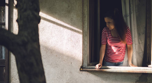 istock Young beautiful sad woman leaning on window sill 1032740266