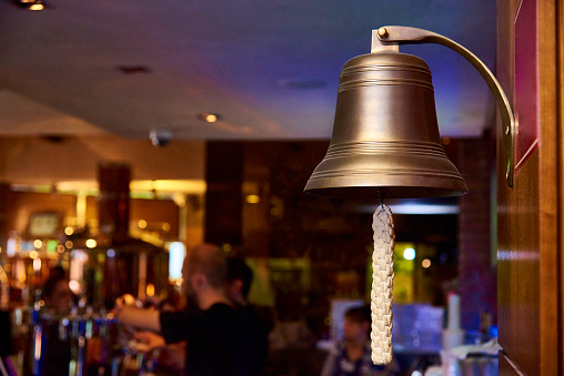 A sea bell with a woven rope on a blurred bar background.