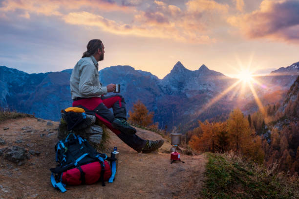 Climber enjoys coffee at sunrise in Alps