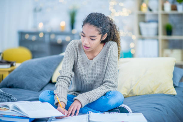 istock Teen does homework on her bed at home 1032771396
