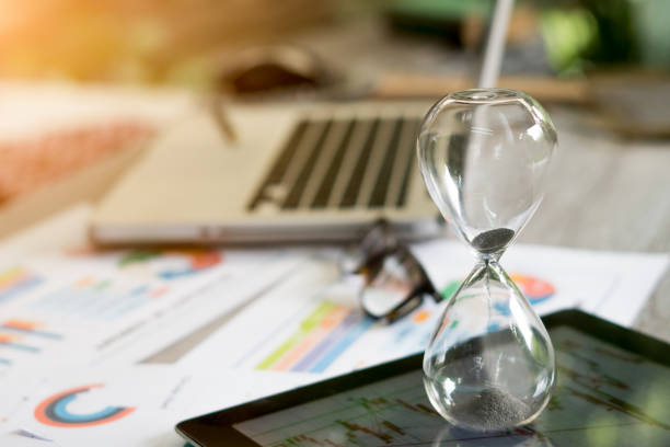 istock Hourglass standing on table with sand trickling, man working with graphs, data, stock footage 1032782394