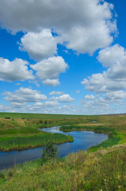 istock Sunny summer landscape with river,fields,green hills and beautiful clouds in blue sky. 1032789892