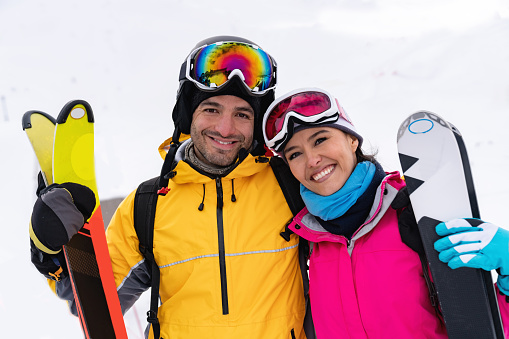 Portrait of a happy loving couple skiing and looking at the camera smiling â winter lifestyle concepts