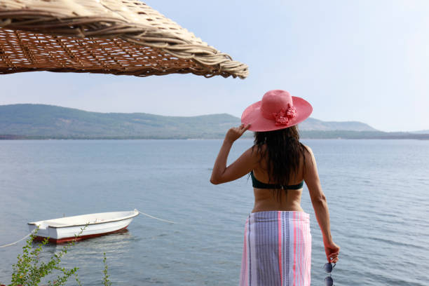 Young woman in hat standing on beach. rear view