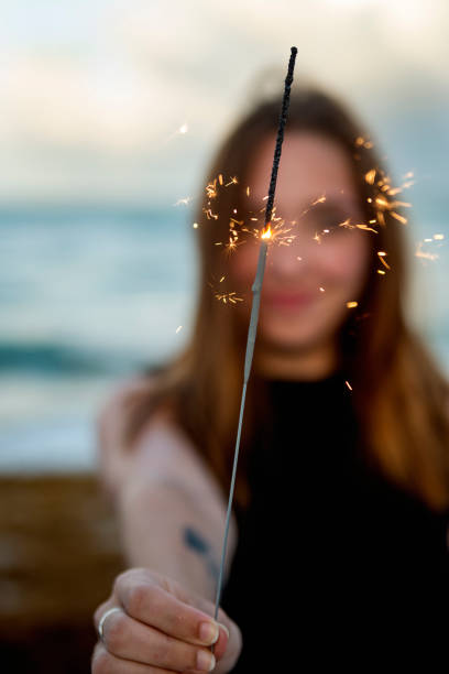 istock Young woman playing with sparklers on the beach at dusk 1032851780