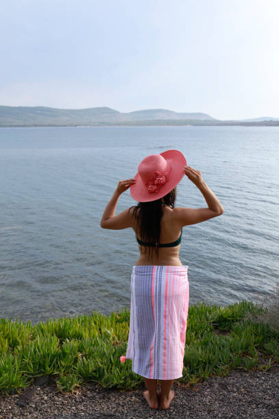 istock Young woman in hat standing on beach. rear view 1032859286