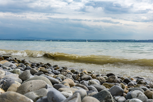 Wave and colorful stones at Lake Constance. Stone beach.