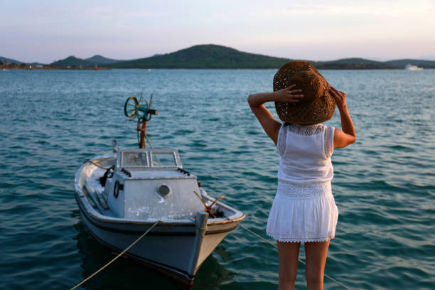 istock Young woman in hat standing on beach. rear view 1032863172