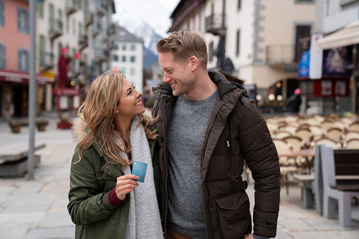 Portrait of a happy couple using their credit card while enjoying their winter holidays in a village in France - lifestyle concepts. **DESIGN ON CARD WAS MADE FROM SCRATCH BY US**