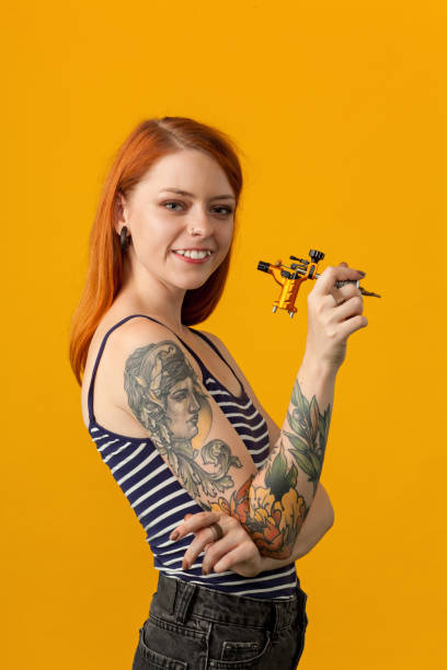 retrato de estudio de un tatuador sobre un fondo amarillo - tattoo machine fotografías e imágenes de stock