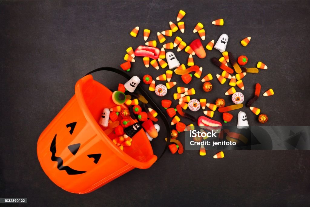 Halloween Jack o Lantern pail, top view with spilling candy Halloween Jack o Lantern pail with spilling candy, above view on a dark background Halloween Stock Photo