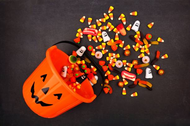 Halloween Jack o Lantern pail, top view with spilling candy Halloween Jack o Lantern pail with spilling candy, above view on a dark background halloween treats stock pictures, royalty-free photos & images