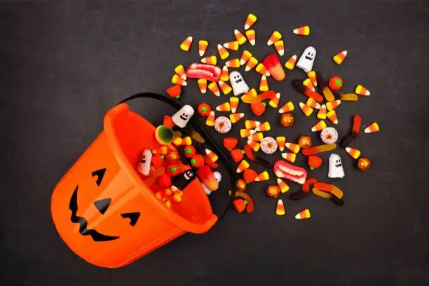 Photo of Halloween Jack o Lantern pail, top view with spilling candy