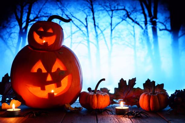 istock Halloween Jack o Lanterns against spooky blue lit forest 1032890822