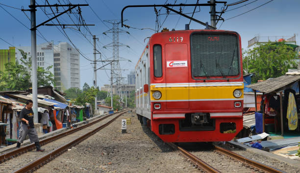 Jakarta Commuter Line Train A commuter train drives through a shanty town right next to the business district of Jakarta, where poverty contrasts with modern office in the background on a sunny day in Indonesia jakarta slums stock pictures, royalty-free photos & images