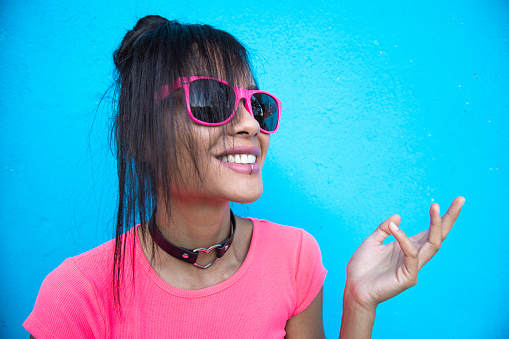 Smiling woman in pink outfit on blue background.