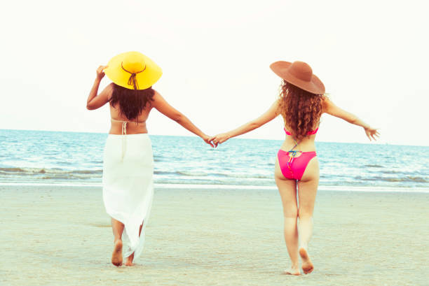 istock Happy women go sunbathing at sand beach in summer. 1032940804