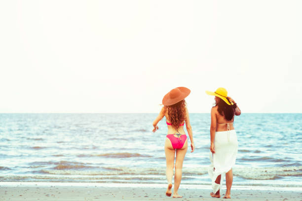 istock Happy women go sunbathing at sand beach in summer. 1032940818