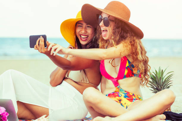 istock Happy women taking photo on sand beach in summer. 1032940820