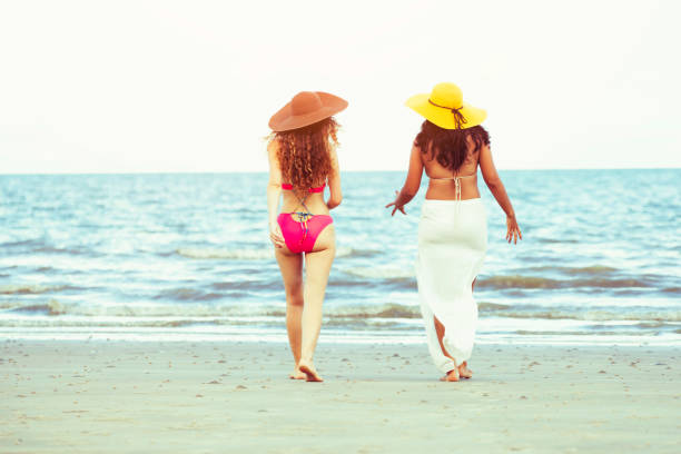 istock Happy women go sunbathing at sand beach in summer. 1032940828