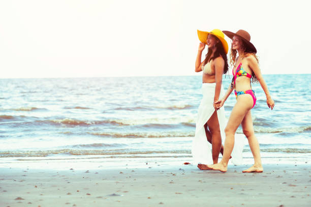 istock Happy women go sunbathing at sand beach in summer. 1032940844