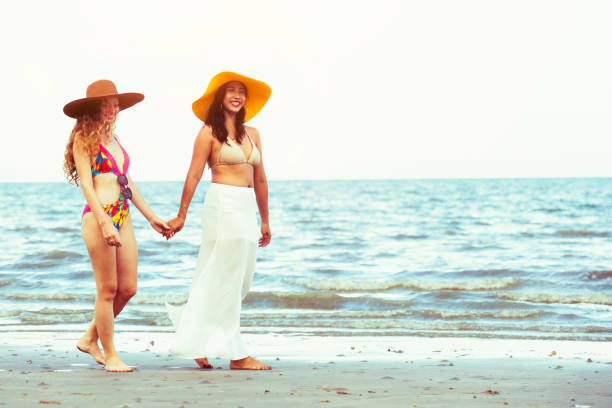 istock Happy women go sunbathing at sand beach in summer. 1032940884