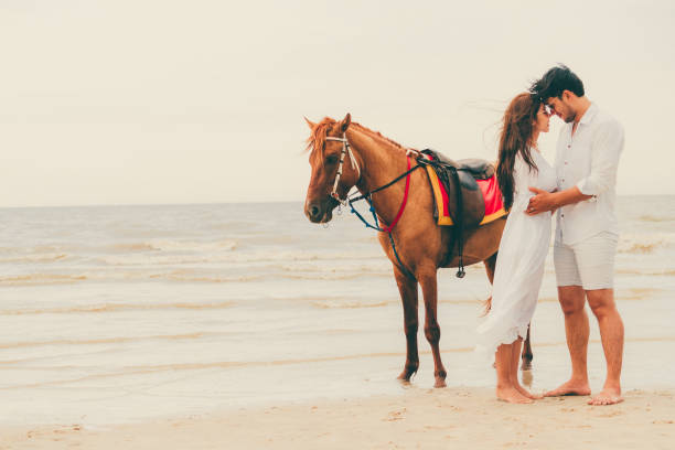 istock Young couple goes horse riding on tropical beach. 1032940996