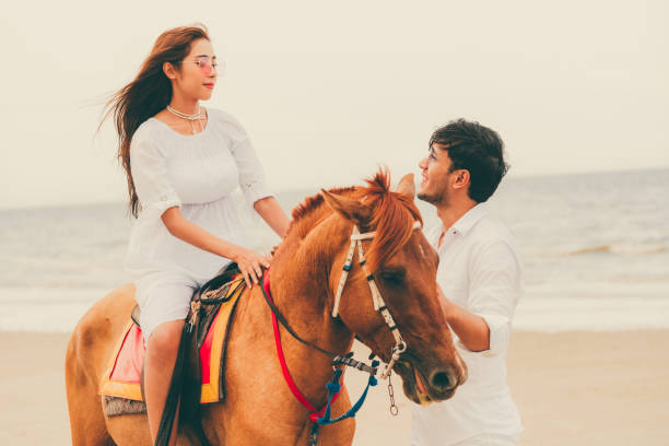 istock Young couple goes horse riding on tropical beach. 1032940998